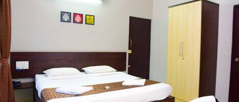 A hotel room with a bed, a wardrobe, a nightstand, and a wall-mounted light fixture.