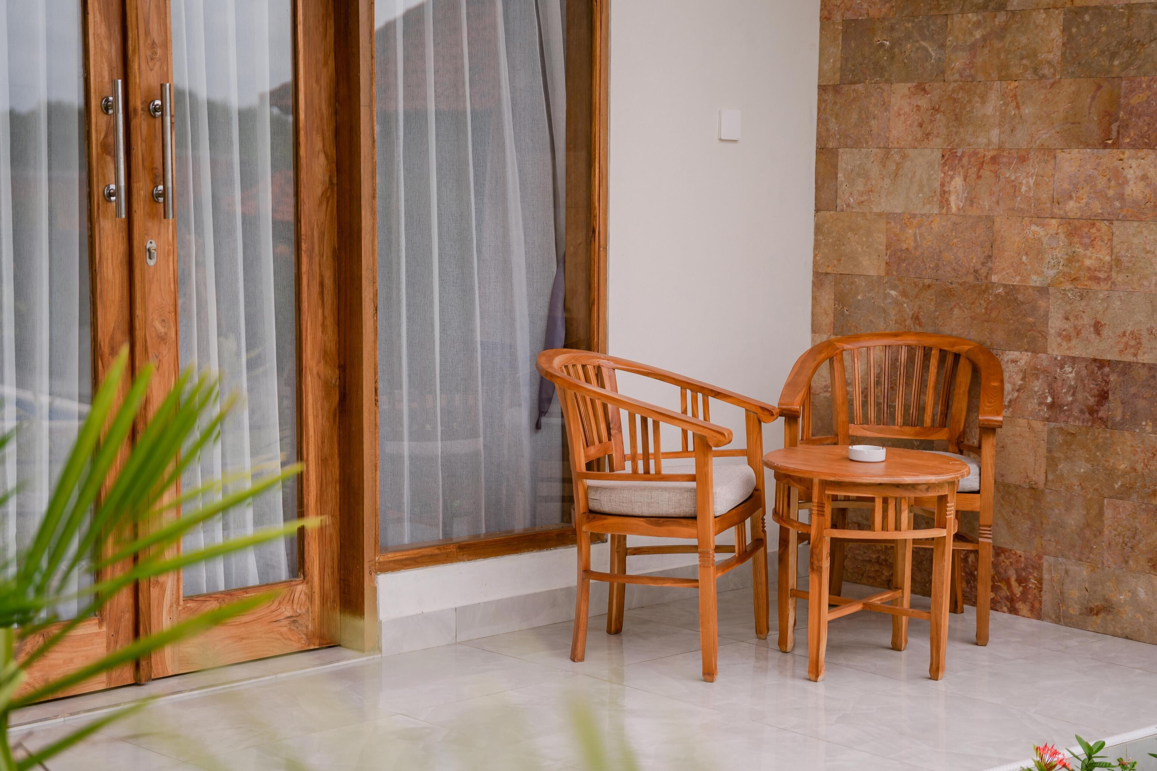 Un ensemble de table et de chaise en bois, placé devant un mur de pierre, avec une porte-fenêtre coulissante en arrière-plan.