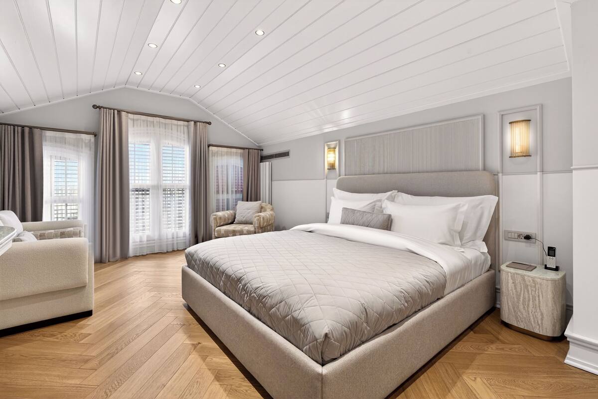 A modern bedroom with a large bed, a chair, and a nightstand.