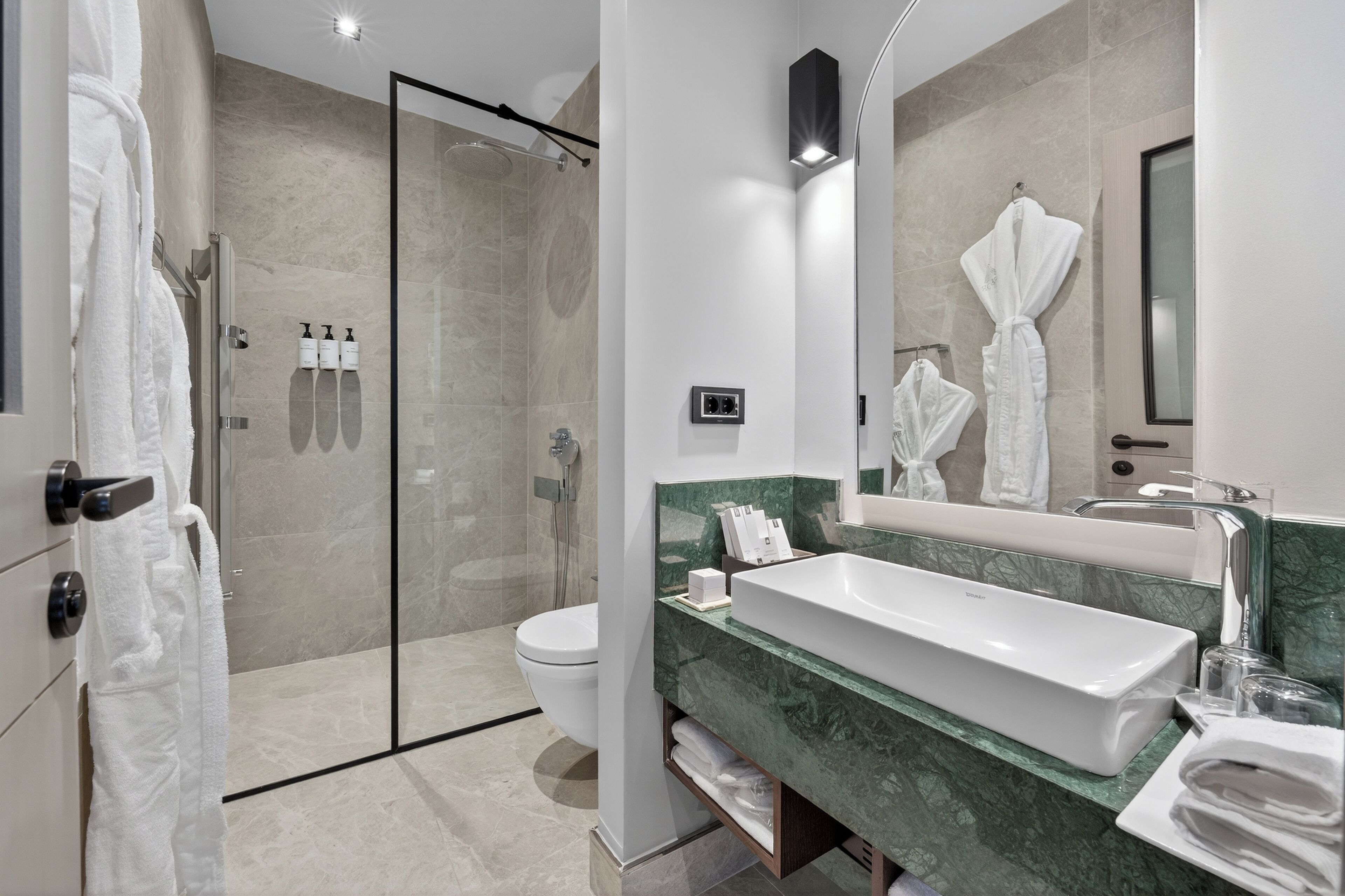 A modern bathroom with a glass shower enclosure, a white sink, and a large mirror.