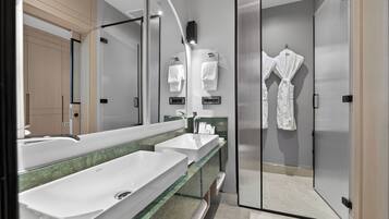 Un baño moderno con tres lavamanos, un espejo grande y una cabina de ducha de vidrio.