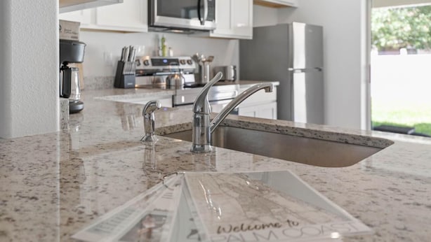 A kitchen with a granite countertop, stainless steel sink, and modern appliances.