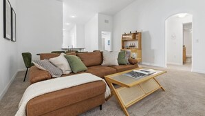 A modern living room with a brown sectional sofa, a coffee table, and a bookshelf.