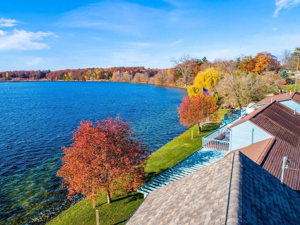 Una propiedad junto al lago con vista al agua, una bandera y follaje otoñal.