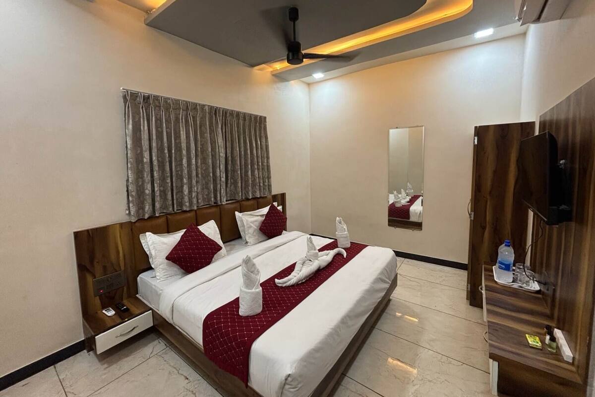 A hotel room with a bed, nightstands, a mirror, a wardrobe, and a ceiling fan.