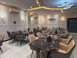 A conference room with multiple tables and chairs, air conditioning units, and modern lighting fixtures. - Hotel Sky Moon (Bhilwara)