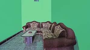A living room with a sofa and a small table against a green wall. - SPOT ON 92475 Rc Homestay Syariah (Banyuwangi)
