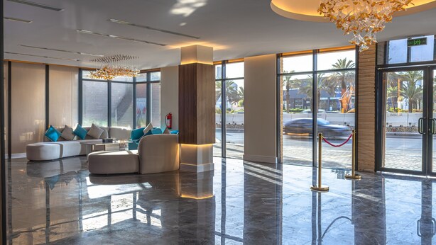 A modern lobby with a seating area, large windows, and a chandelier. - Royal Palace Hotel - Financial District (Riyadh)