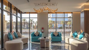 A modern lobby with large windows, two sofas, a coffee table, and a decorative chandelier. - Royal Palace Hotel - Financial District (Riyadh)