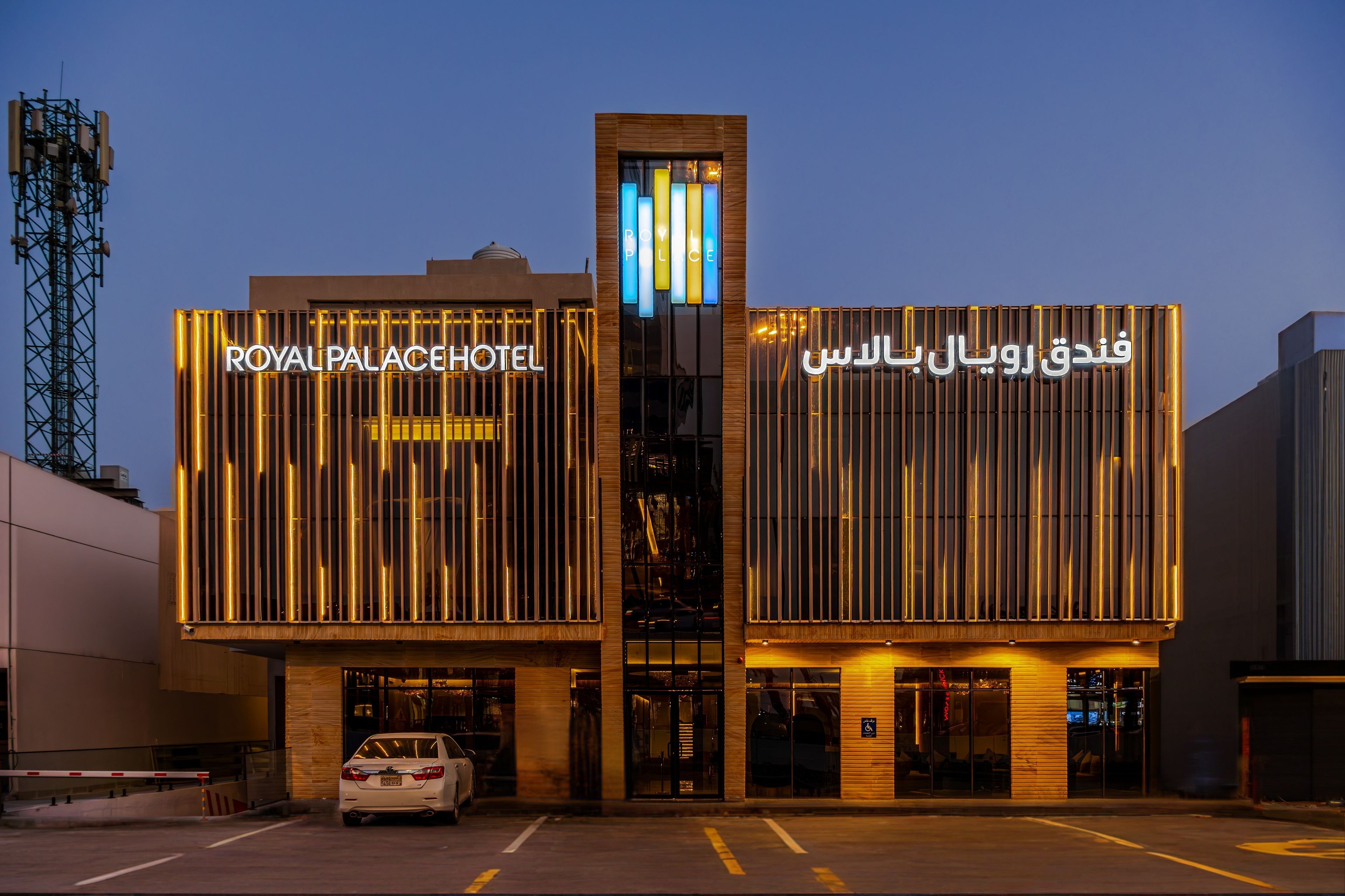 A hotel with a modern facade, featuring illuminated signage in both English and Arabic.