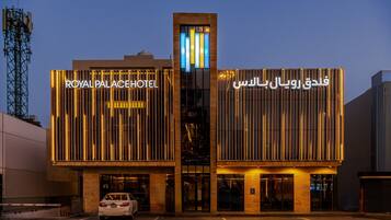A hotel with a modern facade, featuring illuminated signage in both English and Arabic.