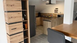 A modern kitchen with wooden cabinetry, a built-in island, and a black refrigerator. - "Weiher Lounge" vacation apartment in the tranquil village of Huppenbroich (Simmerath)