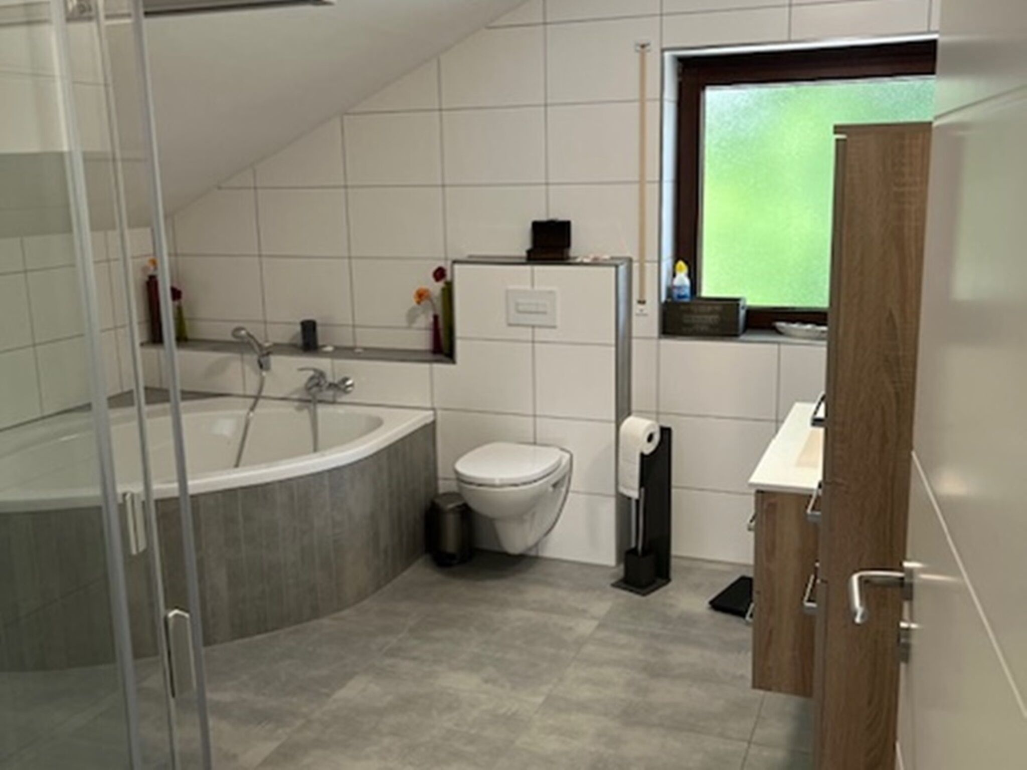 Ein modernes Badezimmer mit Badewanne, Toilette und einer Duschkabine aus Glas.