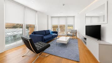 Een moderne woonkamer met een bank, een salontafel, een televisie en een stoel.