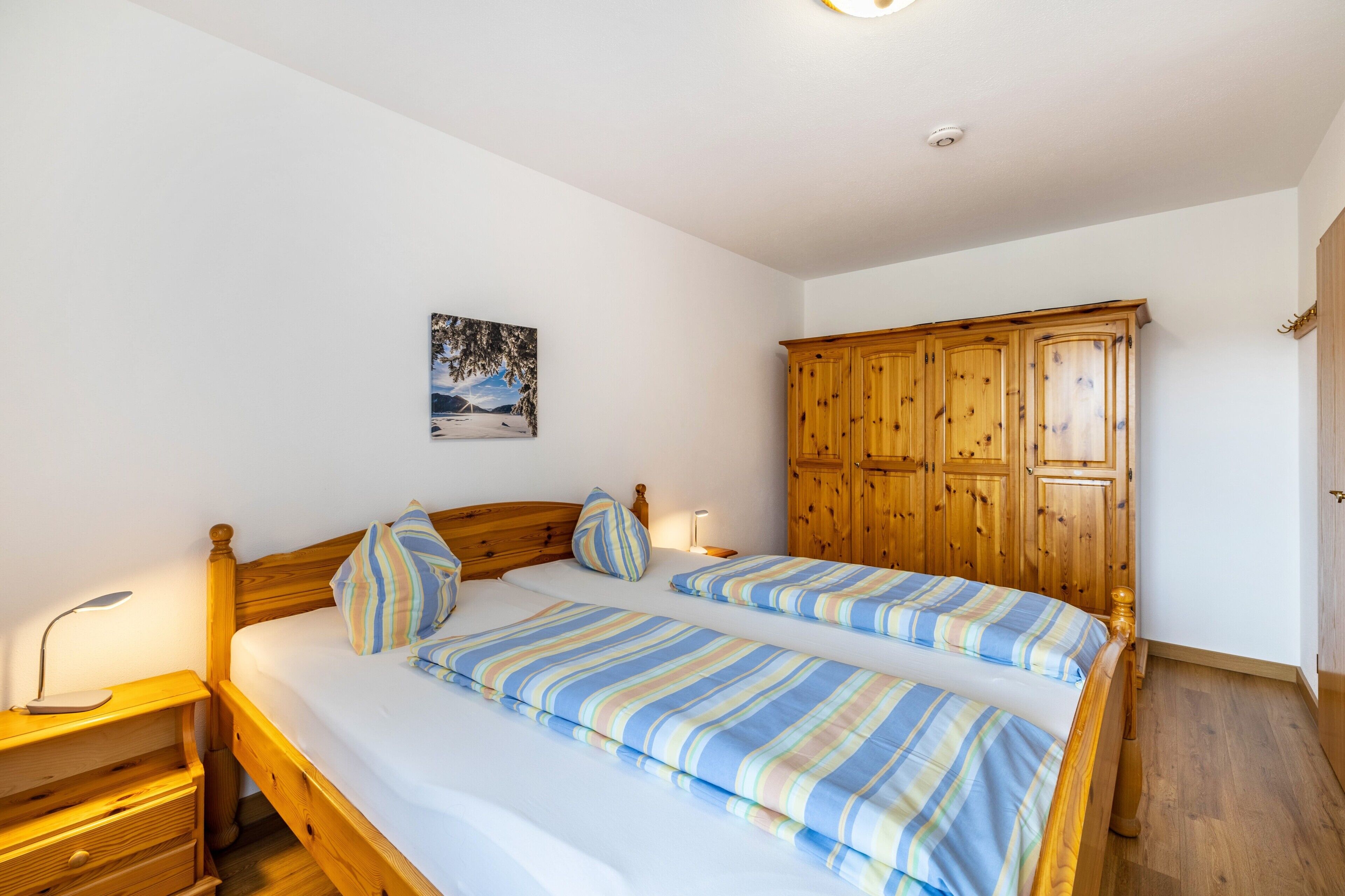 Ein Schlafzimmer mit Doppelbett, Holz-Kopfstütze, Nachttisch, Lampe und Kleiderschrank.
