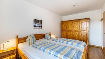 Ein Schlafzimmer mit Doppelbett, Holz-Kopfstütze, Nachttisch, Lampe und Kleiderschrank.