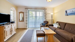 A living room with a television, wooden furniture, a sofa, a table, and a window with curtains.