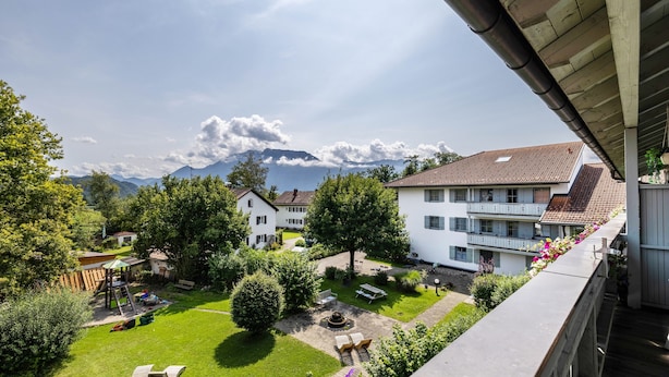 A residential area with a well-maintained garden, a play area, and a view of mountains in the background.