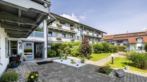 A multi-story hotel with a garden courtyard, outdoor seating, and a visible entrance.