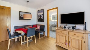 Ein kompakter Wohnbereich mit Essplatz, einer Couch, einem Fernseher und einer Küchenzeile.