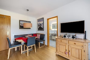 A compact living space with a dining area, a sofa, a TV, and a kitchen area. - Studio 'Brünnstein- No. 13' with Mountain View, Private Terrace, Shared Pool & Sauna (Oberaudorf)