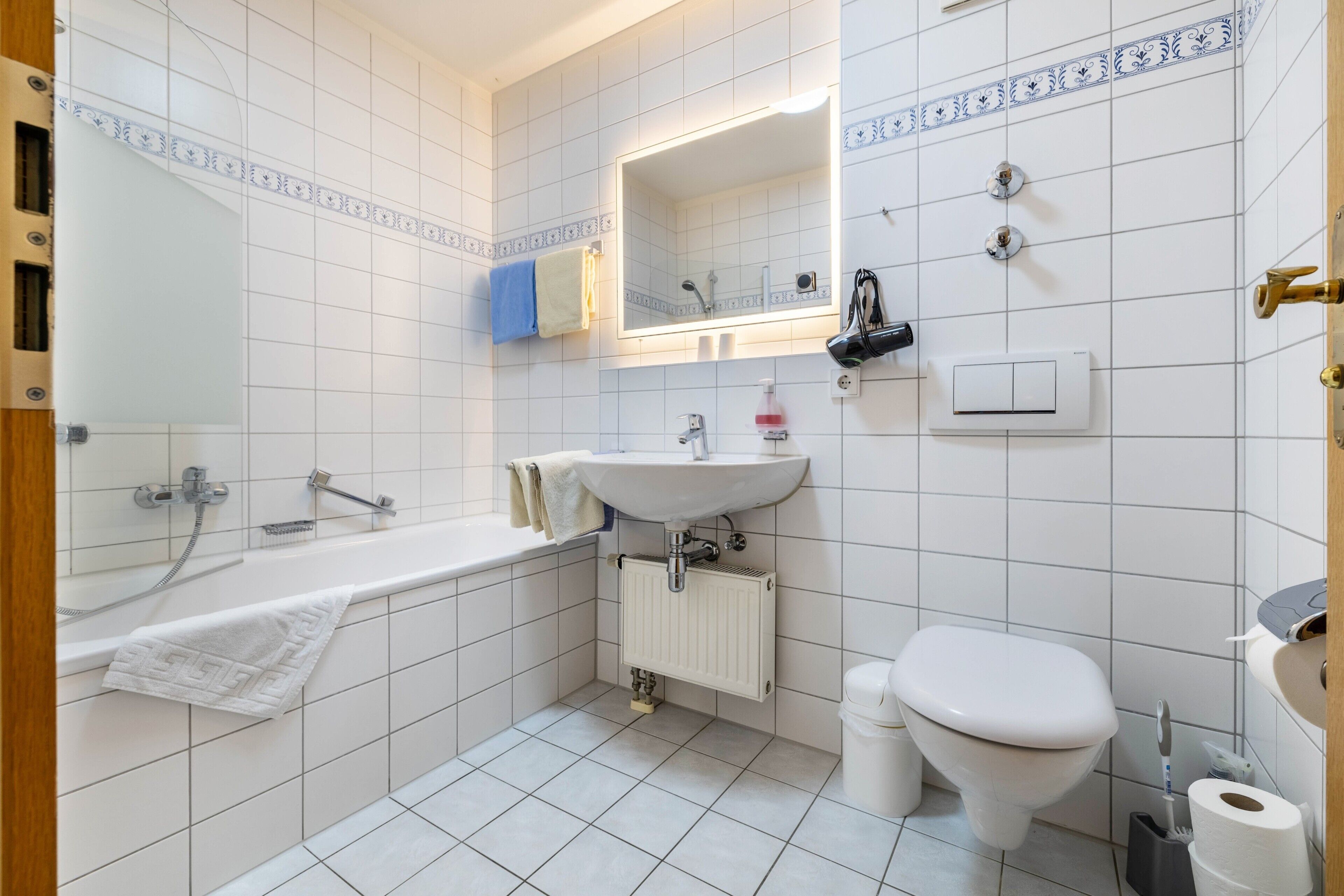Un baño con bañera, lavamanos, inodoro y espejo.