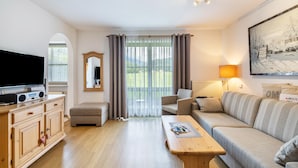 Ein Wohnzimmer mit Fernseher, Holzschrank, Sofa und Tisch.