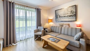 Ein Wohnzimmer mit einer Couch, einem Sessel, einem Couchtisch und einem Bild an der Wand.