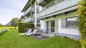Ein modernes Gebäude mit Balkon, Terrasse und Gartenmöbeln sowie einem gepflegten Rasen.