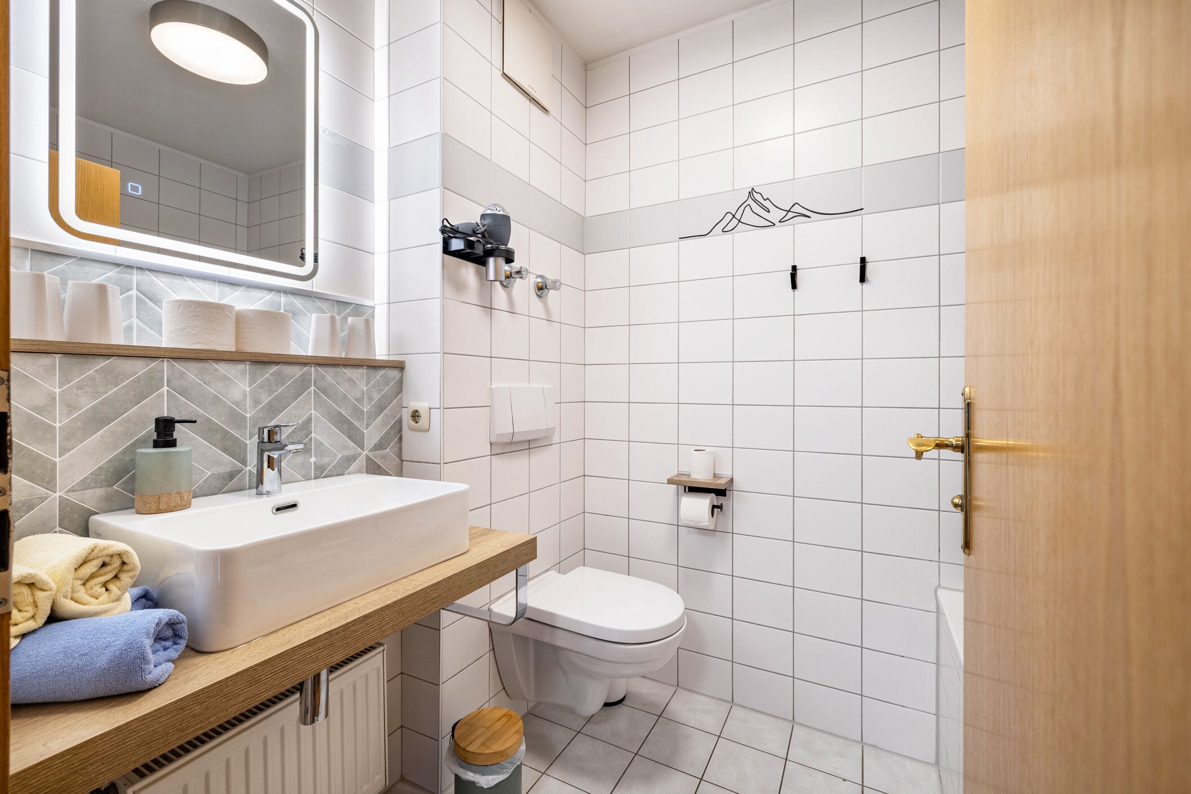 Une salle de bain avec un lavabo blanc, un miroir et des toilettes.