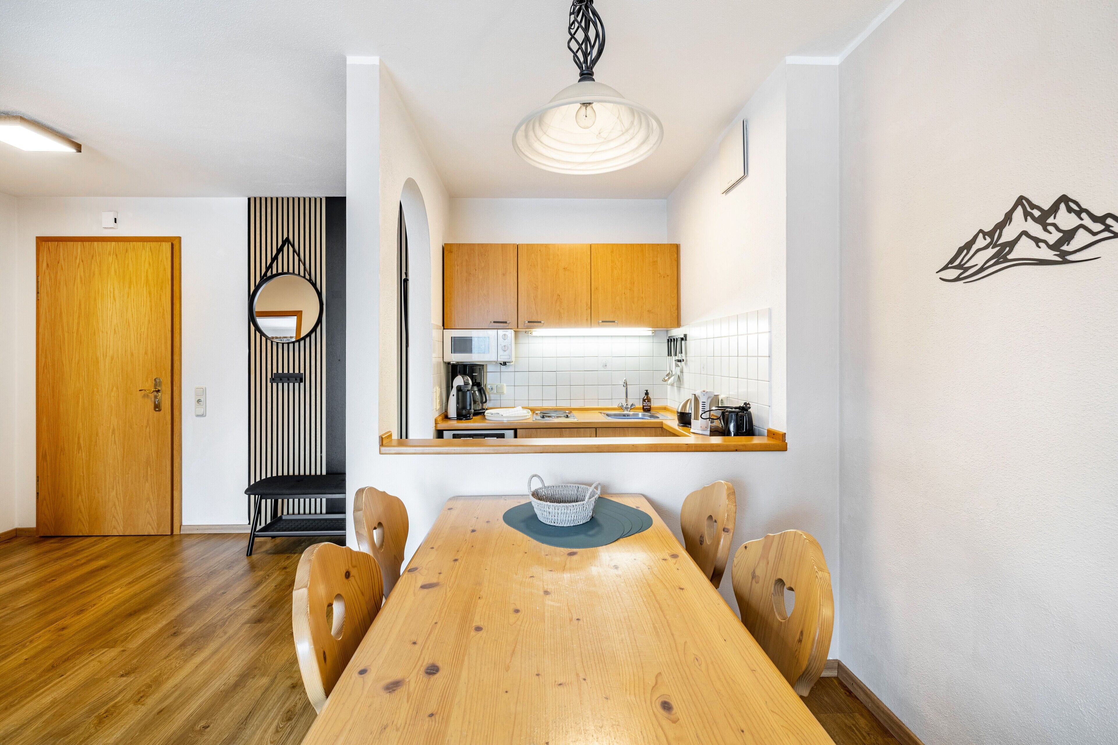 Une cuisine moderne avec des meubles en bois, un four à micro-ondes et un coin repas comprenant une table et des chaises en bois.