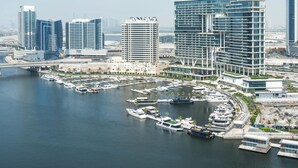 Un port de plaisance où sont amarrés plusieurs bateaux, entouré d’immeubles modernes de grande hauteur.
