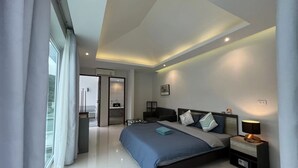 A modern bedroom with a large bed, bedside tables, and a view through a window. - 3bedrooms Pool Villa in Kamala (Kamala)