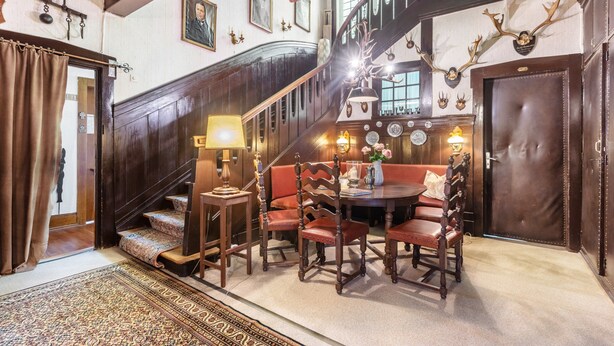 A grand staircase with a wooden finish, a round dining table with chairs, and a chandelier. - Double Room No. 2 with Shared Terrace, Shared Garden and Wi-Fi (Dachsberg (Südschwarzwald))