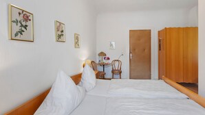 A bedroom with a bed, a wooden wardrobe, a small table with a lamp, and two framed pictures on the wall. - Double Room No. 4 with Mountain View, Shared Terrace and Wi-Fi (Dachsberg (Südschwarzwald))