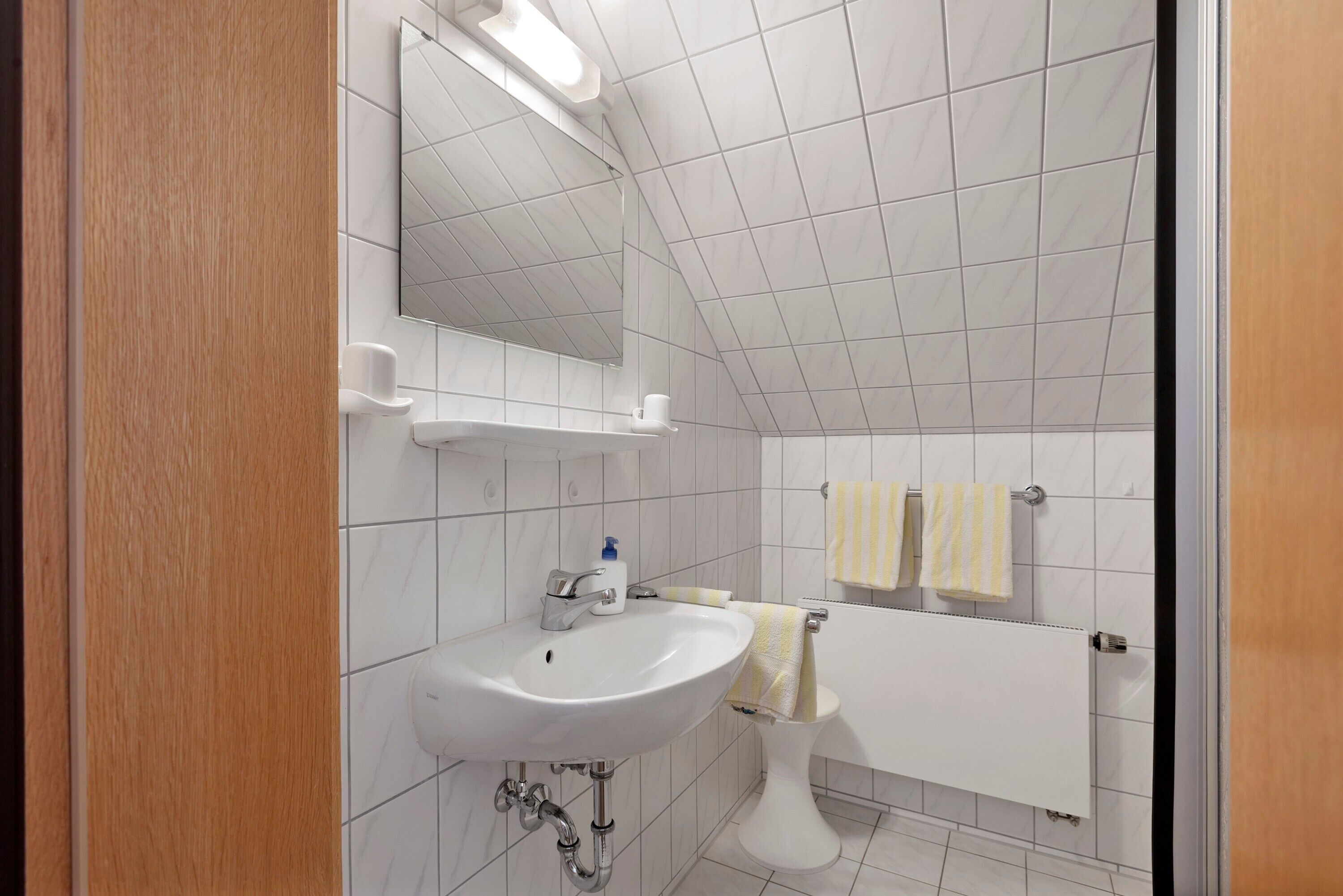 Une salle de bain avec un lavabo blanc, un miroir et des toilettes.