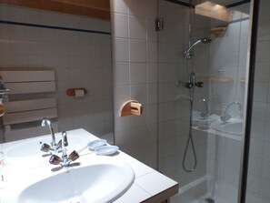 Un bagno con un lavandino bianco, due rubinetti e un box doccia in vetro.