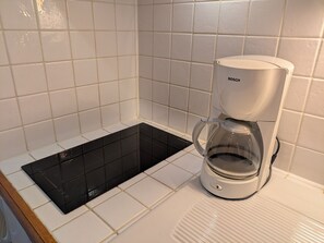 Une cuisine avec des carreaux blancs, une machine à café Bosch et une plaque de cuisson à induction noire.