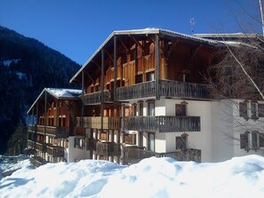 Un chalet in legno con diversi balconi e un paesaggio innevato.