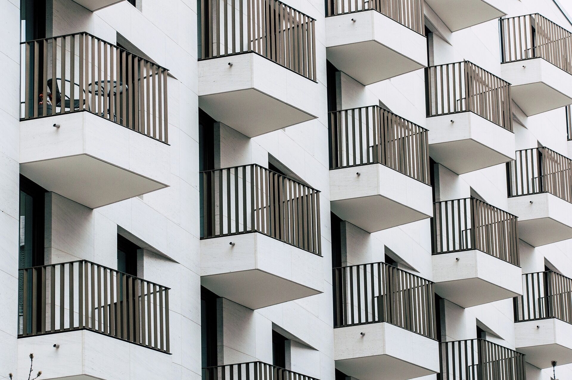Un bâtiment moderne doté de nombreux balcons, avec des garde-corps noirs et des motifs géométriques.