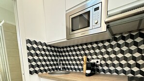 Eine moderne Küche mit Mikrowelle, einer Holz Arbeitsplatte und einer geometrischen Spritzschutzwand.