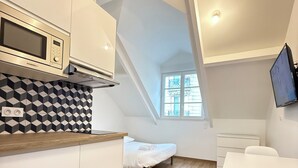 Eine kompakte Küche mit Mikrowelle, ein kleiner Essbereich mit Tisch und Stühlen sowie ein Fenster, das für natürliches Licht sorgt.