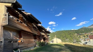A wooden chalet with multiple balconies, a small adjacent building, and a mountainous backdrop. - Apartment at the foot of the slopes in Vars Les Claux, pets allowed (Vars)