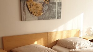 A bedroom with a wooden headboard, two beds with beige bedding, and a wall-mounted abstract artwork. - Apartment '3' with Shared Terrace, Balcony and Wi-Fi (Weil am Rhein)