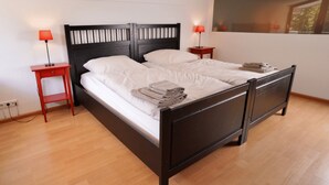 A double bed with a wooden frame, two bedside tables with lamps, and a window with a view. - Apartment '2' with Shared Terrace, Balcony and Wi-Fi (Weil am Rhein)