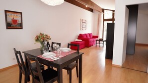 A dining area with a wooden table, chairs, a vase of flowers, and a red sofa in the background. - Apartment '2' with Shared Terrace, Balcony and Wi-Fi (Weil am Rhein)