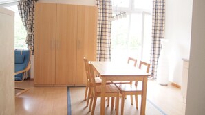 A room with a wooden table and chairs, a blue sofa, and a wardrobe. - Apartment '1' with Shared Terrace, Balcony and Wi-Fi (Weil am Rhein)