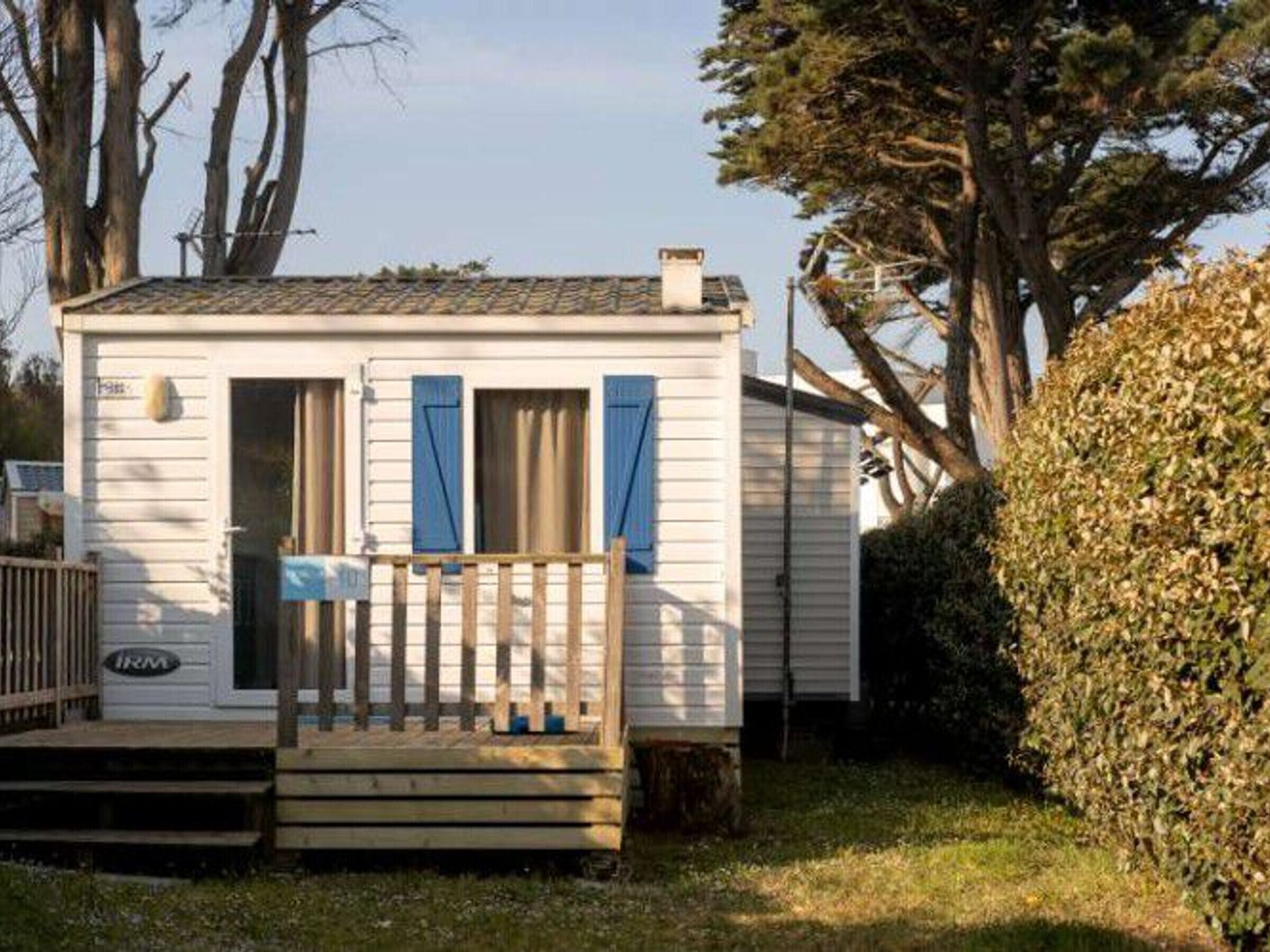 A small, single-story mobile home with a porch and a chimney.