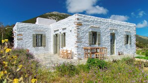 A white stone house with a patio and wooden furniture.