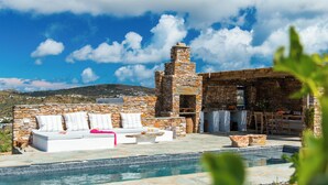 A stone building with a pool, outdoor seating, and a mountain view.